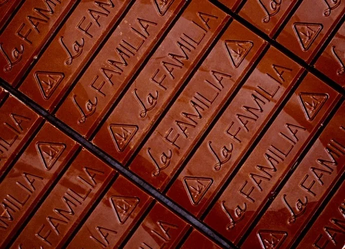 Rows of glossy molded chocolate bars, each embossed with the La Familia script logo and the California THC triangle, artisanal Mexican-inspired cannabis chocolate.